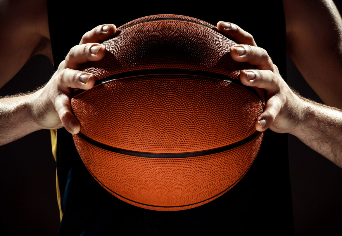 Silhouette view of a basketball player holding basket ball on black background